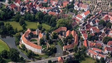 Vista aérea de un pueblo histórico con una imponente fortaleza circular, rodeado de edificios tradicionales y un río.