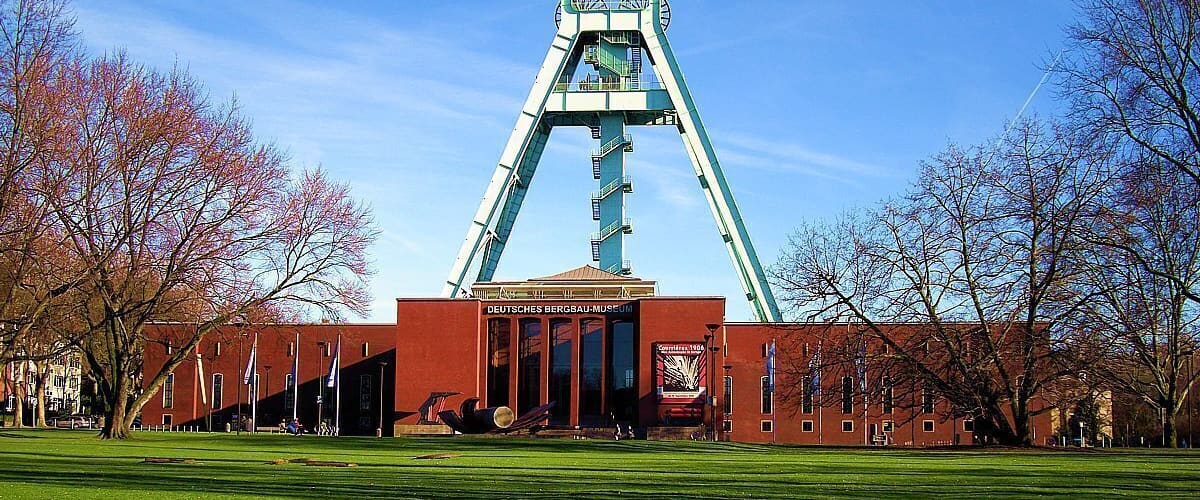 A large open grassy area with a prominent building featuring a tall, triangular structure in the center.