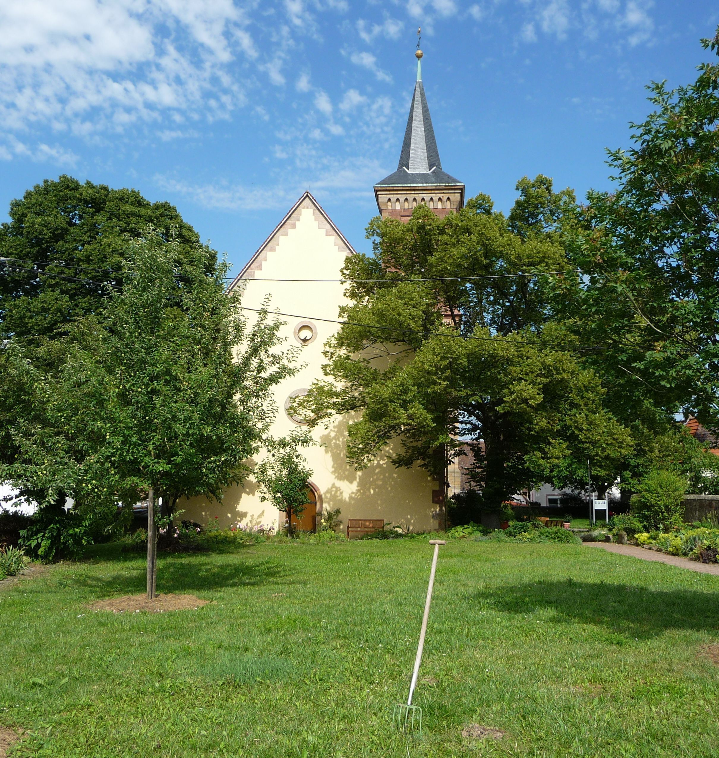 A church with a tall spire and a smaller building with a clock tower.