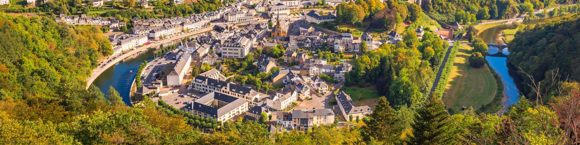 A town nestled in a valley with a river, surrounded by forested hills.