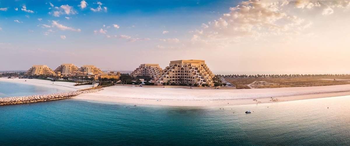 A coastal resort with multiple buildings, a sandy beach, and a calm sea.