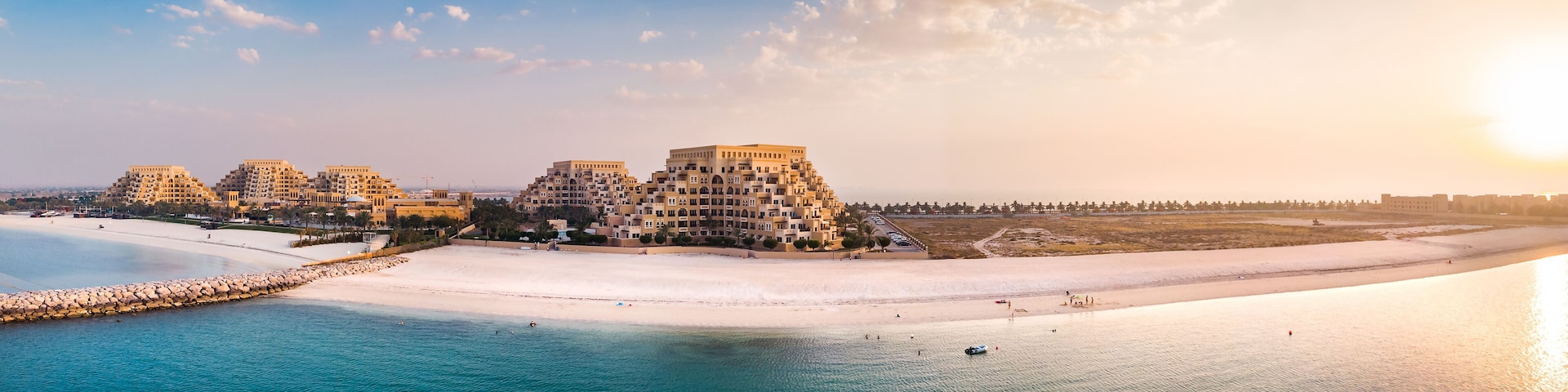 A coastal resort with multiple buildings, a sandy beach, and a calm sea.