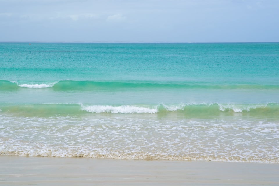 A beach with turquoise water and gentle waves.