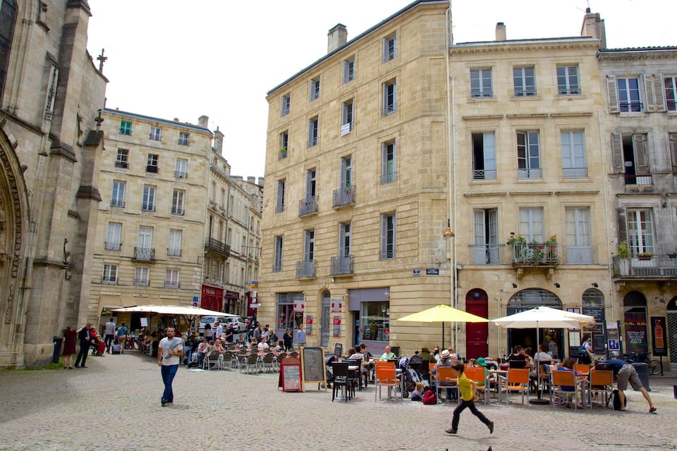 Une place pavée, bordée de cafés en plein air, de bâtiments historiques et d’une cathédrale.