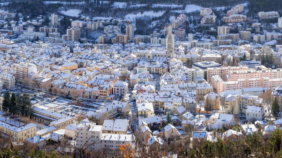 Elevated panoramic view of snow covered rooftops in the city of Gap in winter. Hautes-Alpes, Alps, France