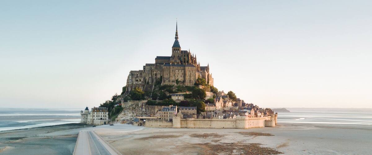 A historic castle on a hill overlooking a beach.