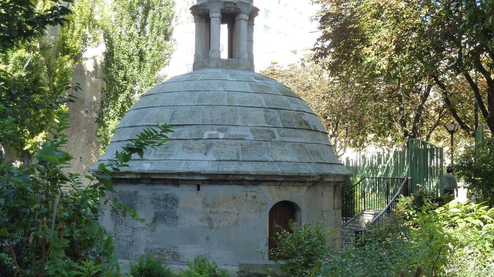 A stone dome structure surrounded by greenery.
