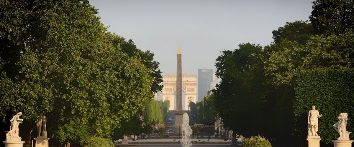 Ein Park mit einem zentralen Brunnen, Statuen und einem hohen Obelisken.