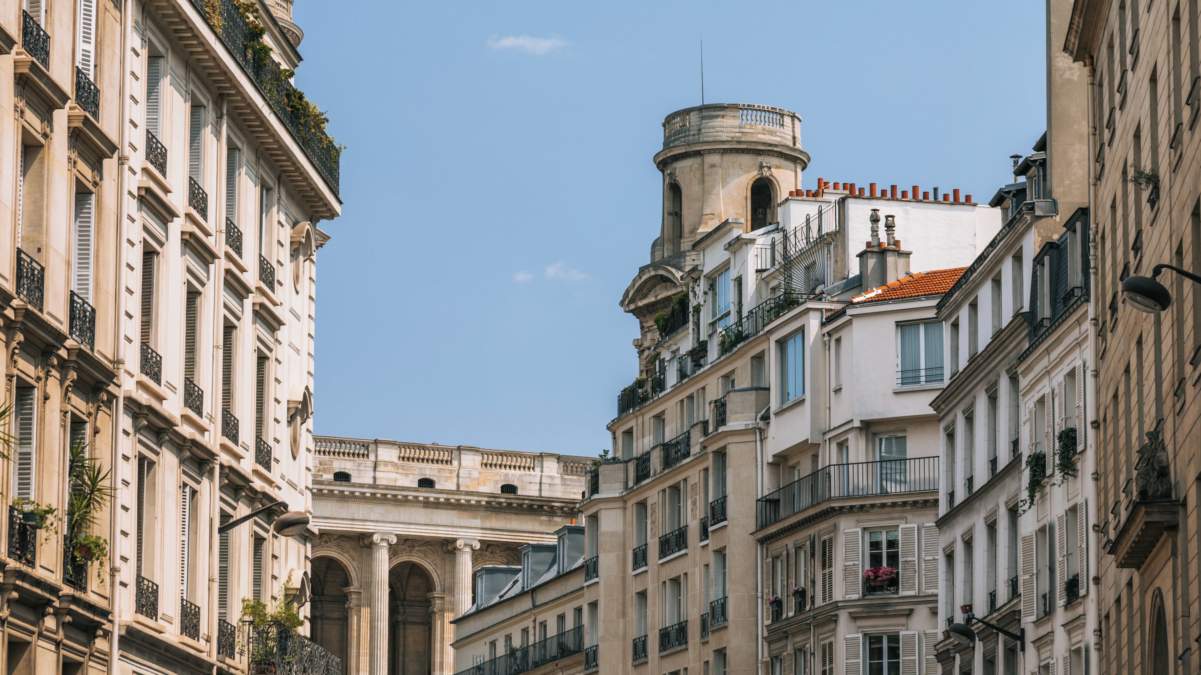 A street with classical architecture, including ornate balconies and a round tower.