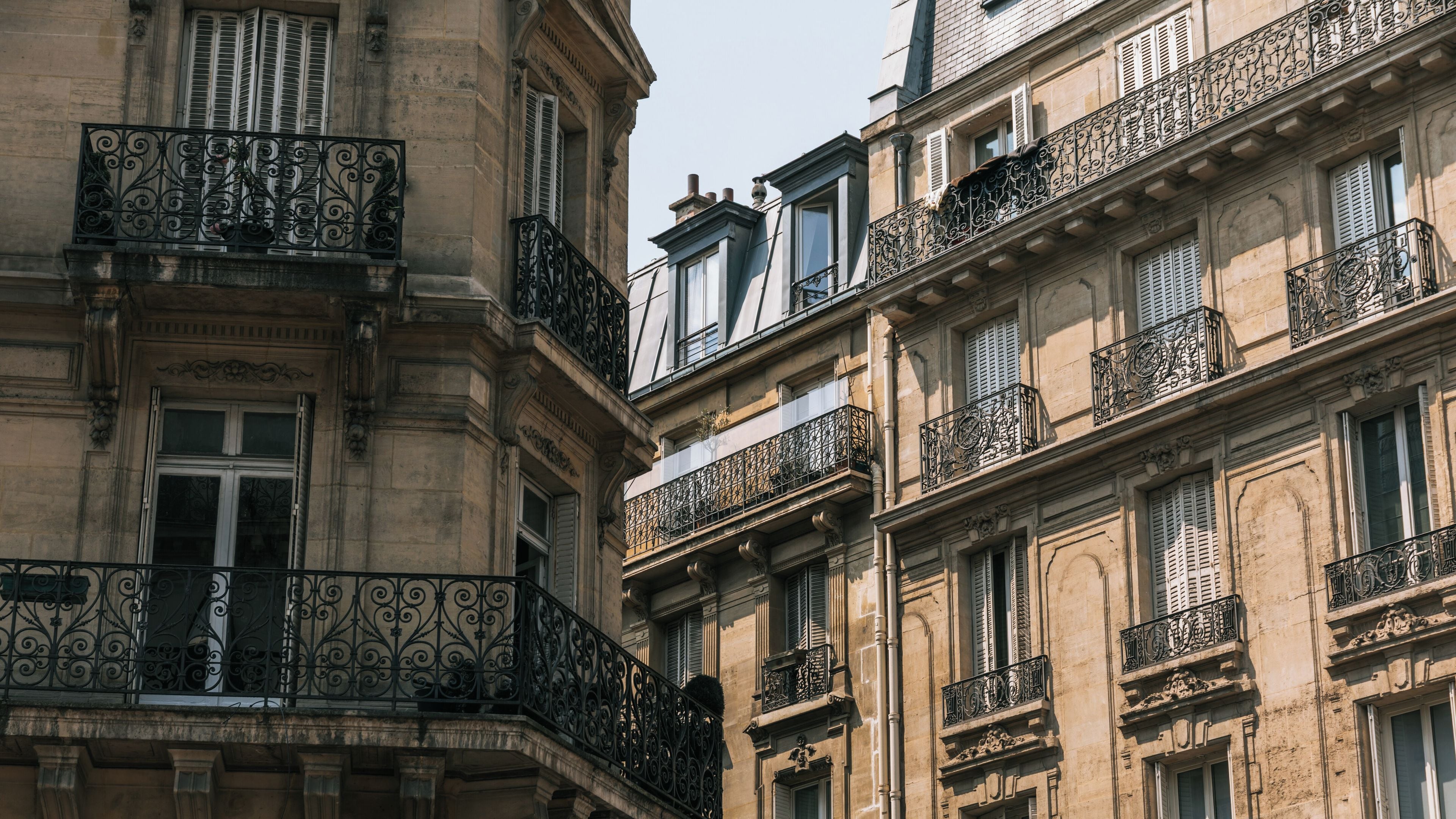 A building with ornate iron balconies and multiple windows with shutters.