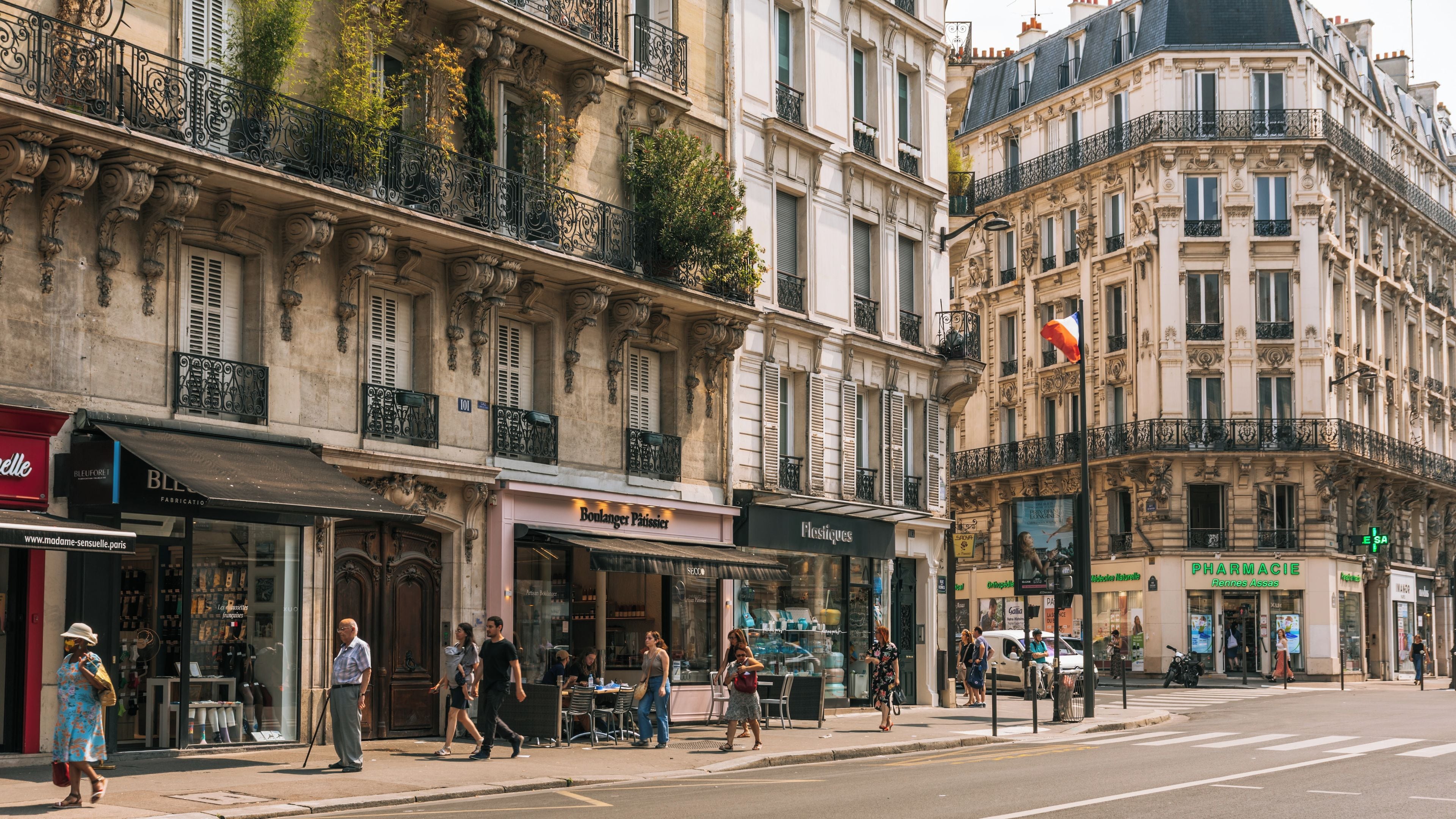 A street with historic buildings, storefronts, and pedestrians.