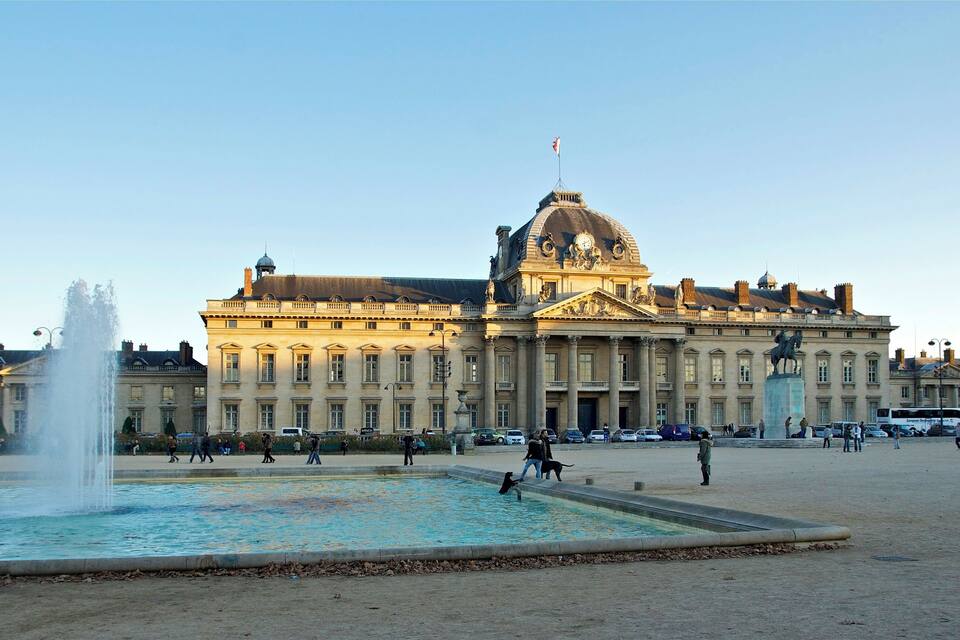 A large historic building with a fountain in front.
