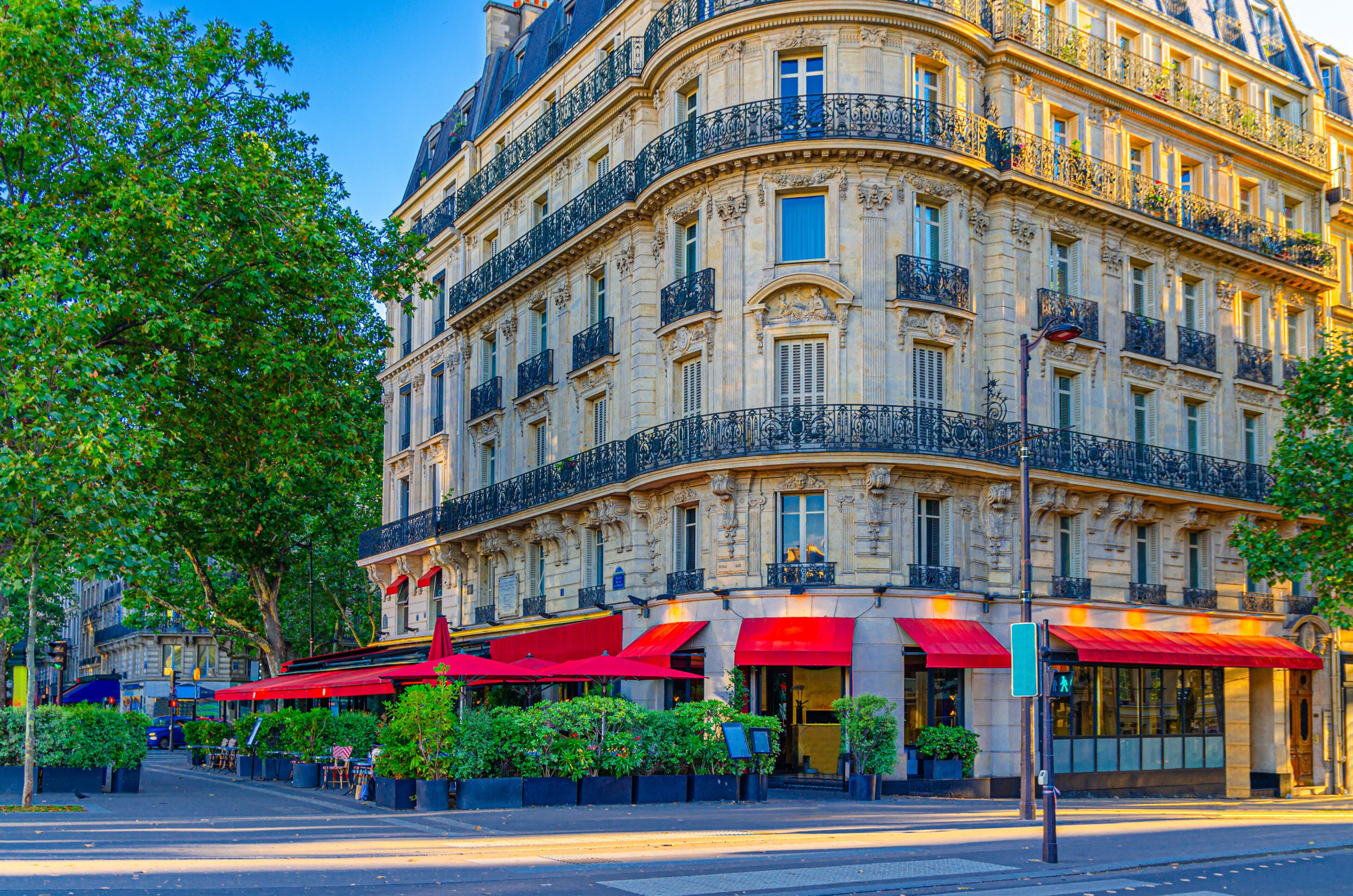 A historic Parisian building with ornate balconies and red awnings.