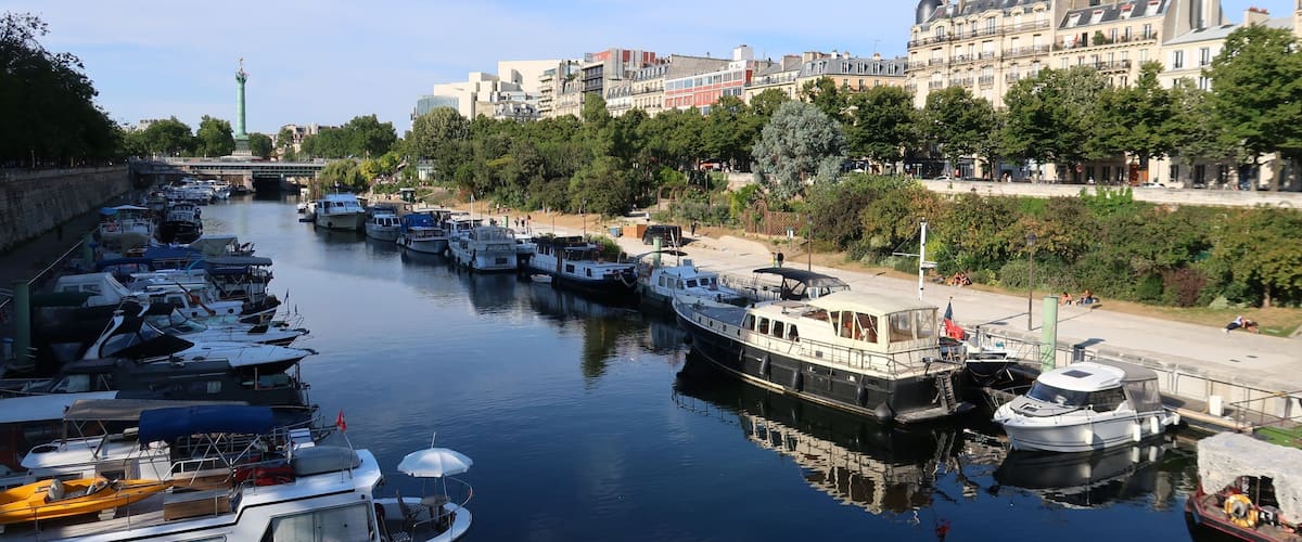 A canal lined with boats, a bridge, and historic buildings.