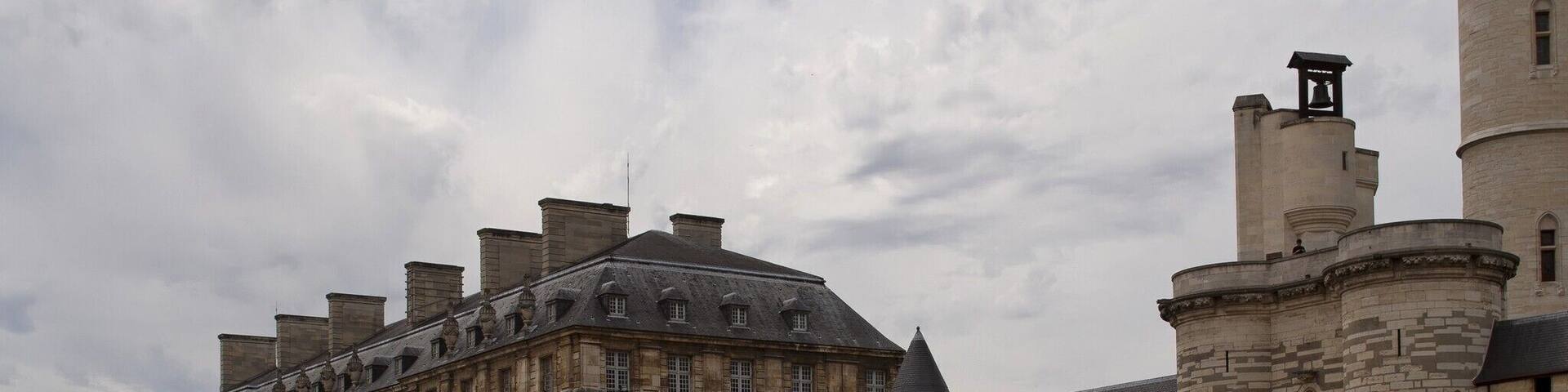 A large historic building with multiple towers and a courtyard.