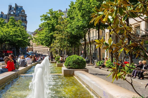 A fountain in a public square surrounded by trees and buildings.