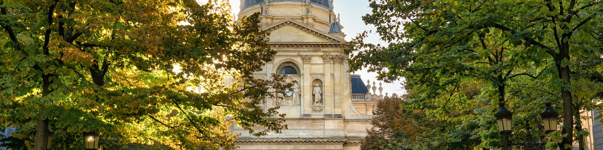 Un bâtiment historique surmonté d’un dôme, entouré d’arbres et agrémenté d’une fontaine.