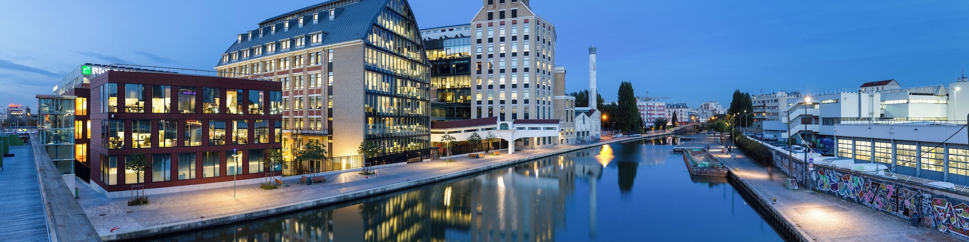 Pantin Mills, and canal of Ourcq, in Pantin, Seine-Saint-Denis, France. Renovated in the years 2000s, Pantin Mills now serve as offices and headquarters for BNP Paribas Securities Services. This picture is a mosaic of 13 pictures each taken at 21mm, f/8.0, 3.5 sec and ISO 100, with a Canon 7D + Canon 17-55 f/2.8 mounted on. Stitching itself was done with Hugin. Resulting horizontal FOV is 164°.