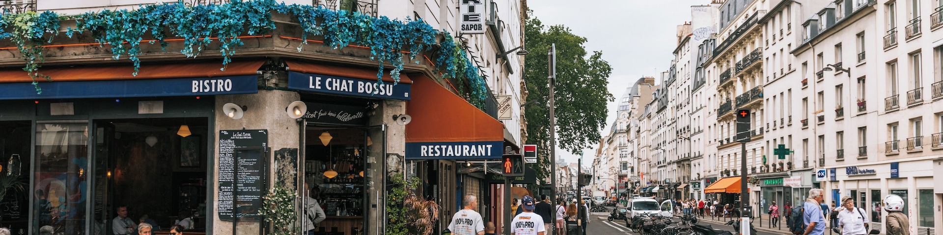 Une rue bordée de cafés et de restaurants, notamment les établissements « BISTRO » et « LE CHAT BOSSU ».