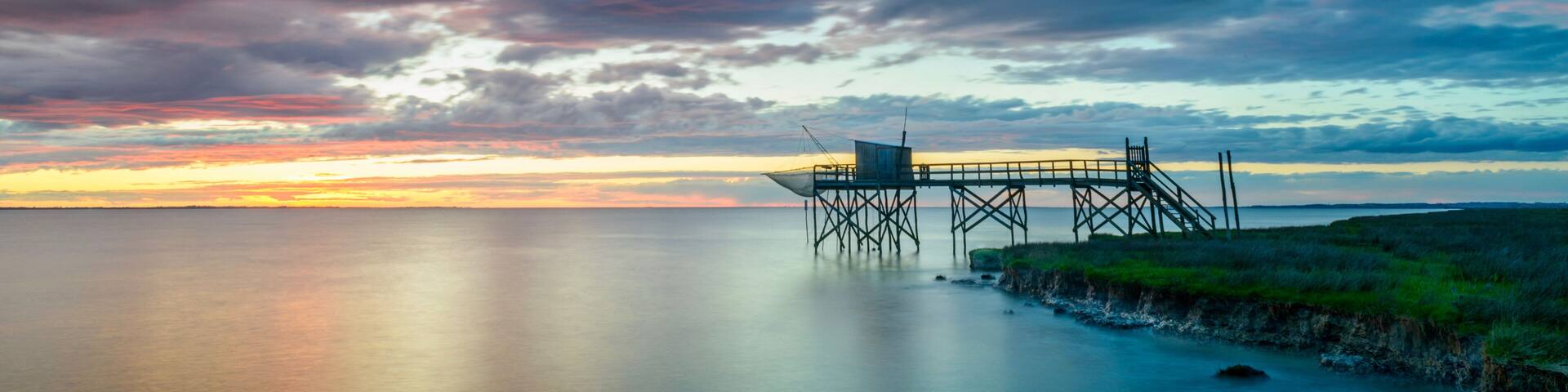 Sunset on Atlantic coast of Charente Maritime, France with traditional fishing hut and calm seas near La Rochelle