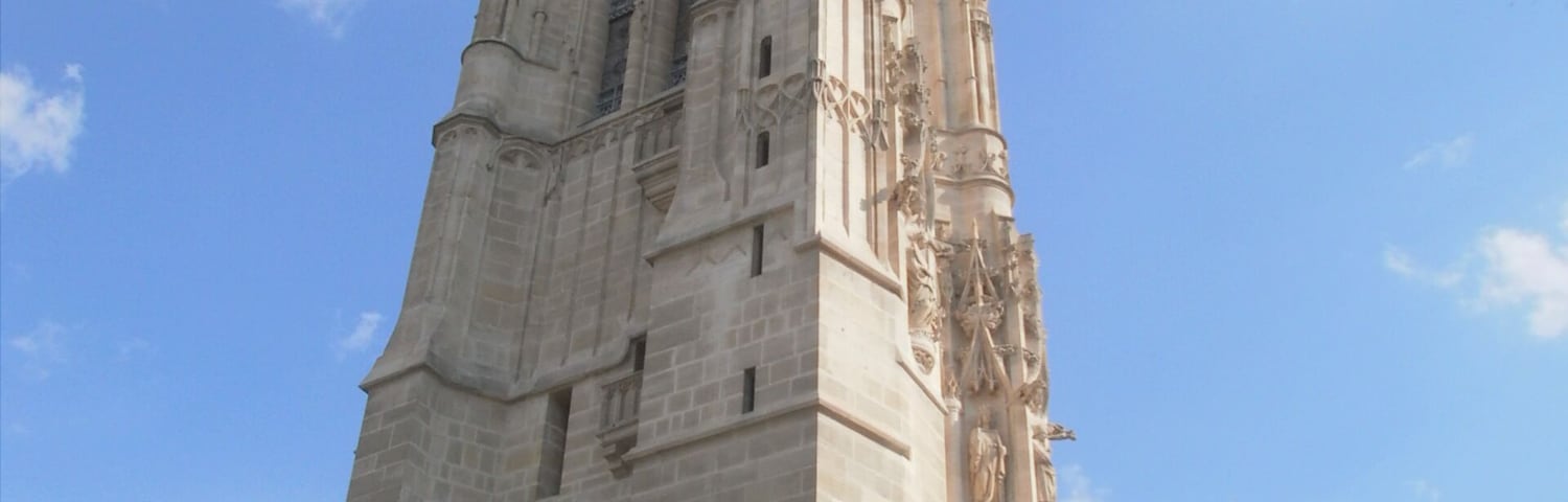 Uma torre alta e ornamentada, com esculturas detalhadas e uma grande entrada em arco na base.