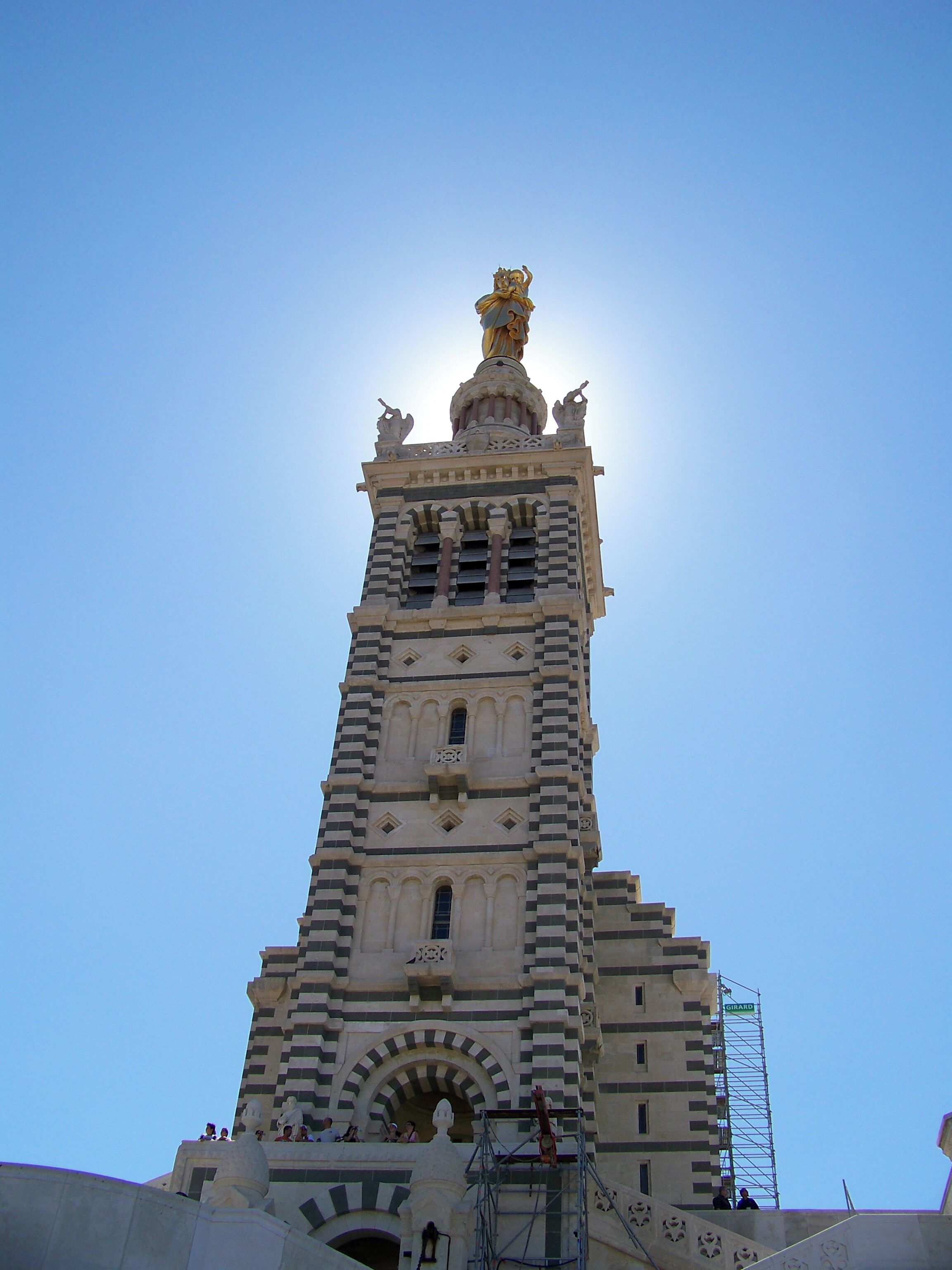 Una torre alta con una estatua en la cima y arcos en la base.
