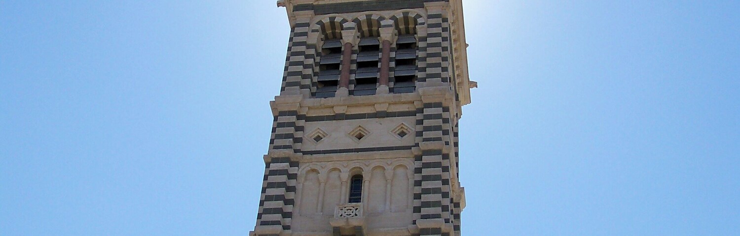 Una torre alta con una estatua en la cima y arcos en la base.