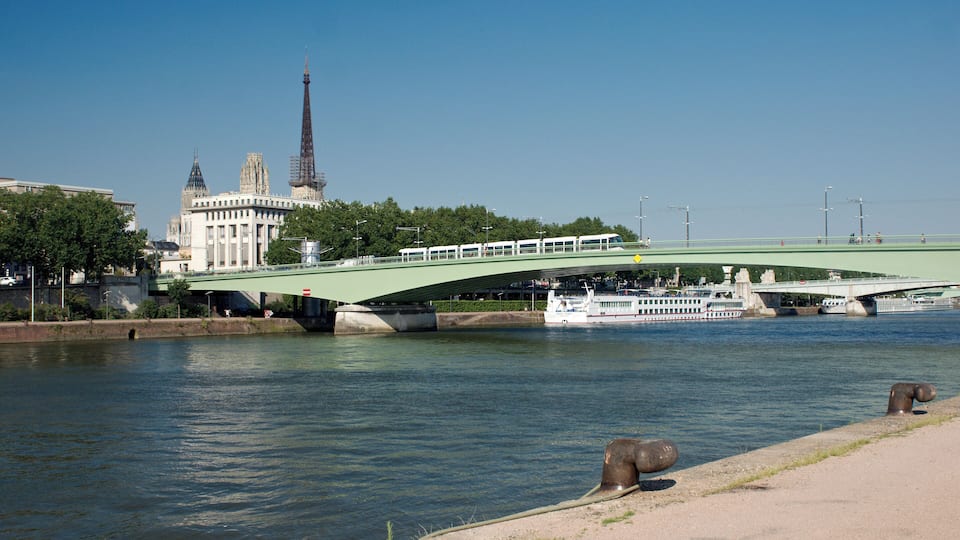 Le pont Jeanne-d’Arc enjambant la Seine à Rouen, avec une nouvelle rame de métro se déplaçant dessus et la cathédrale émergeant au-dessus des immeubles.