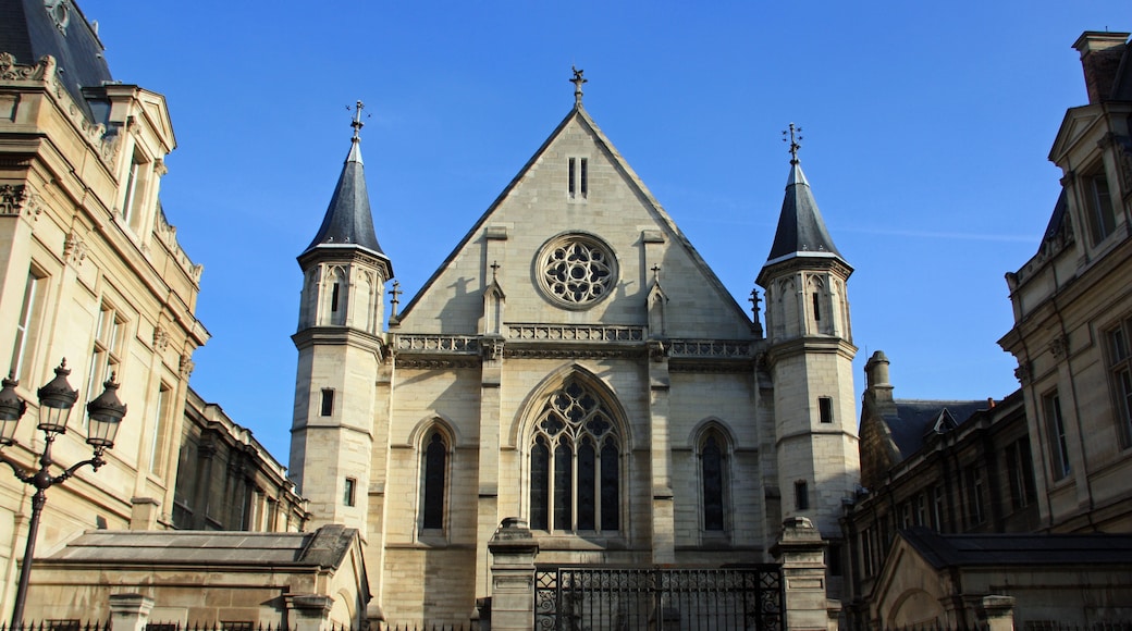 A historic church with a large rose window, two spires, and a gated entrance.