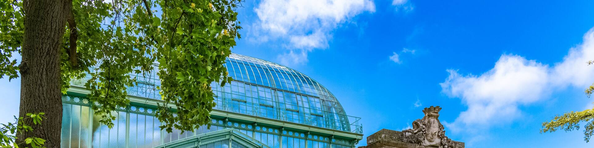 A greenhouse with a glass dome, a fountain, and a statue.