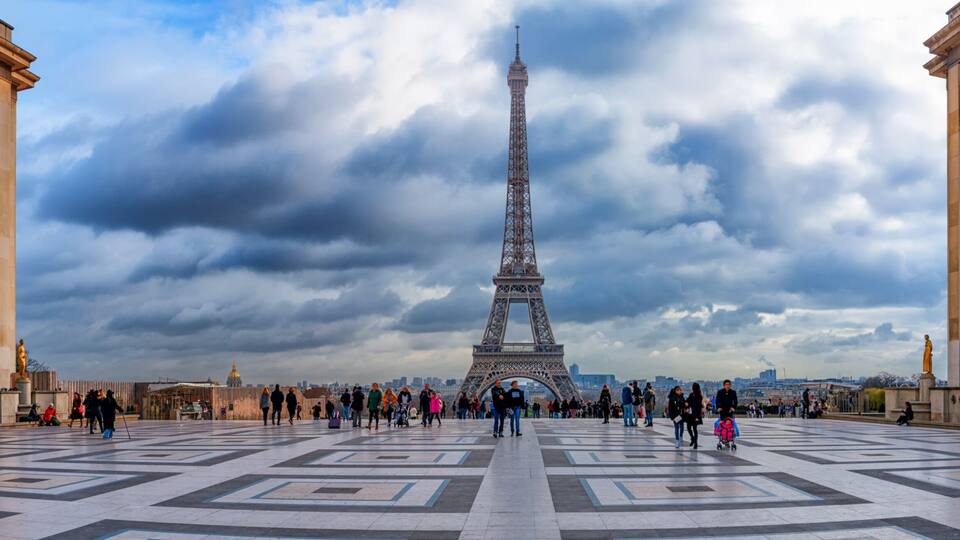 A Torre Eiffel com um céu nublado ao fundo.