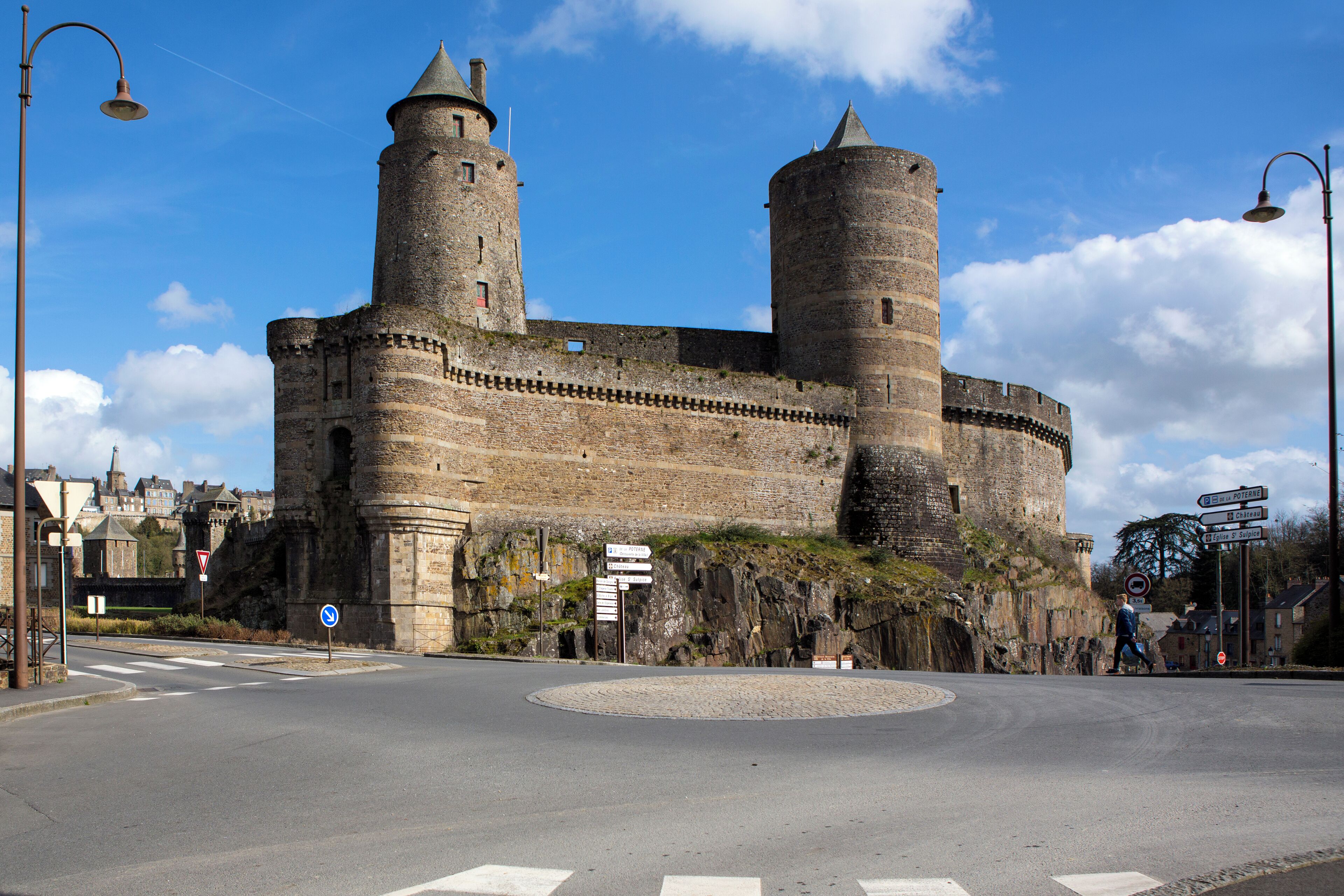 A historic castle with two prominent towers and a roundabout in the foreground.