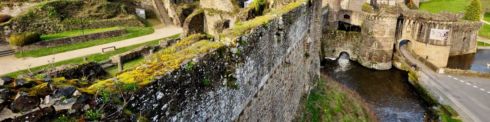 A historic castle with a moat, stone walls, and a small tower.