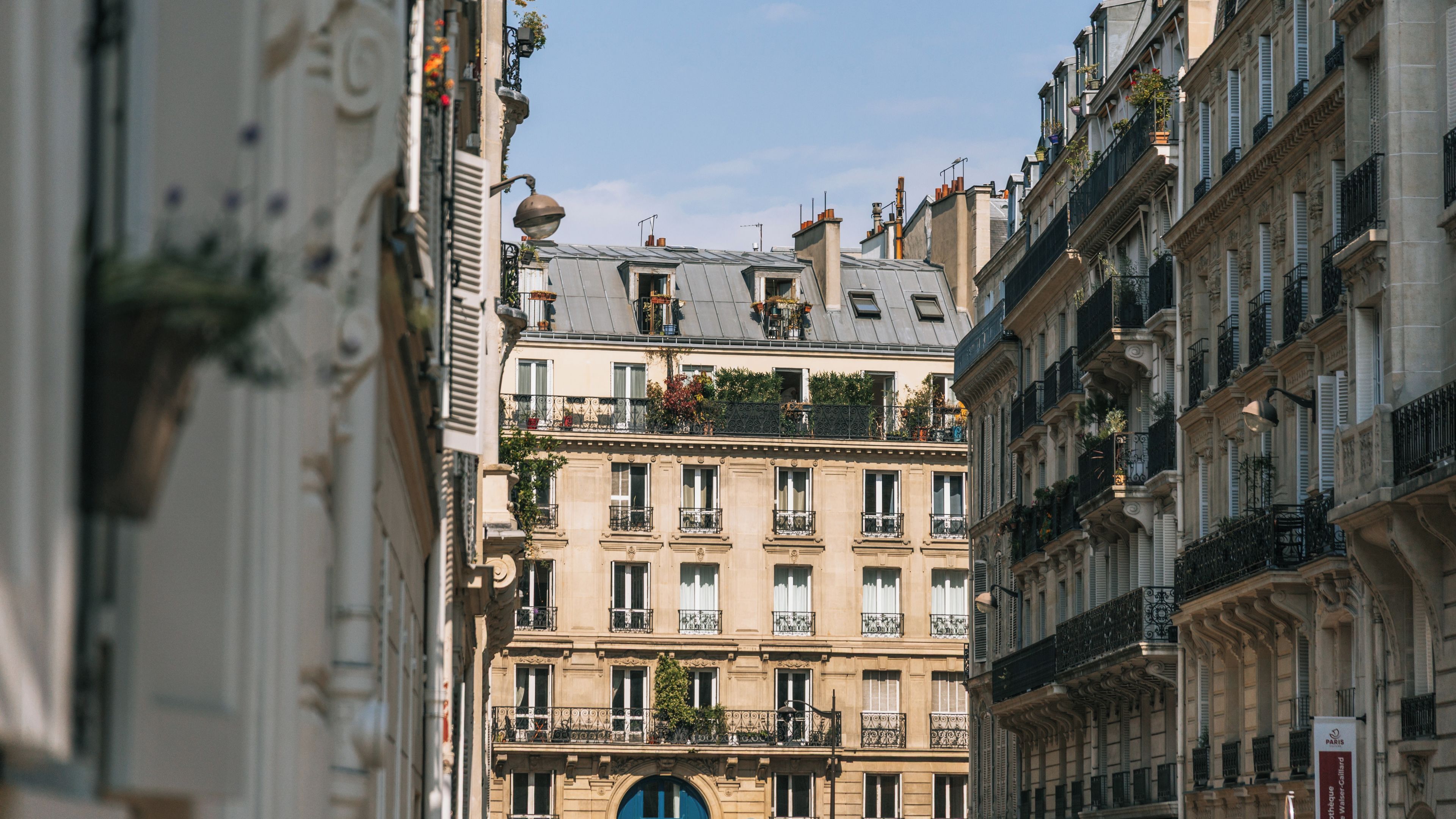 A narrow street flanked by historic buildings with ornate balconies and decorative ironwork.