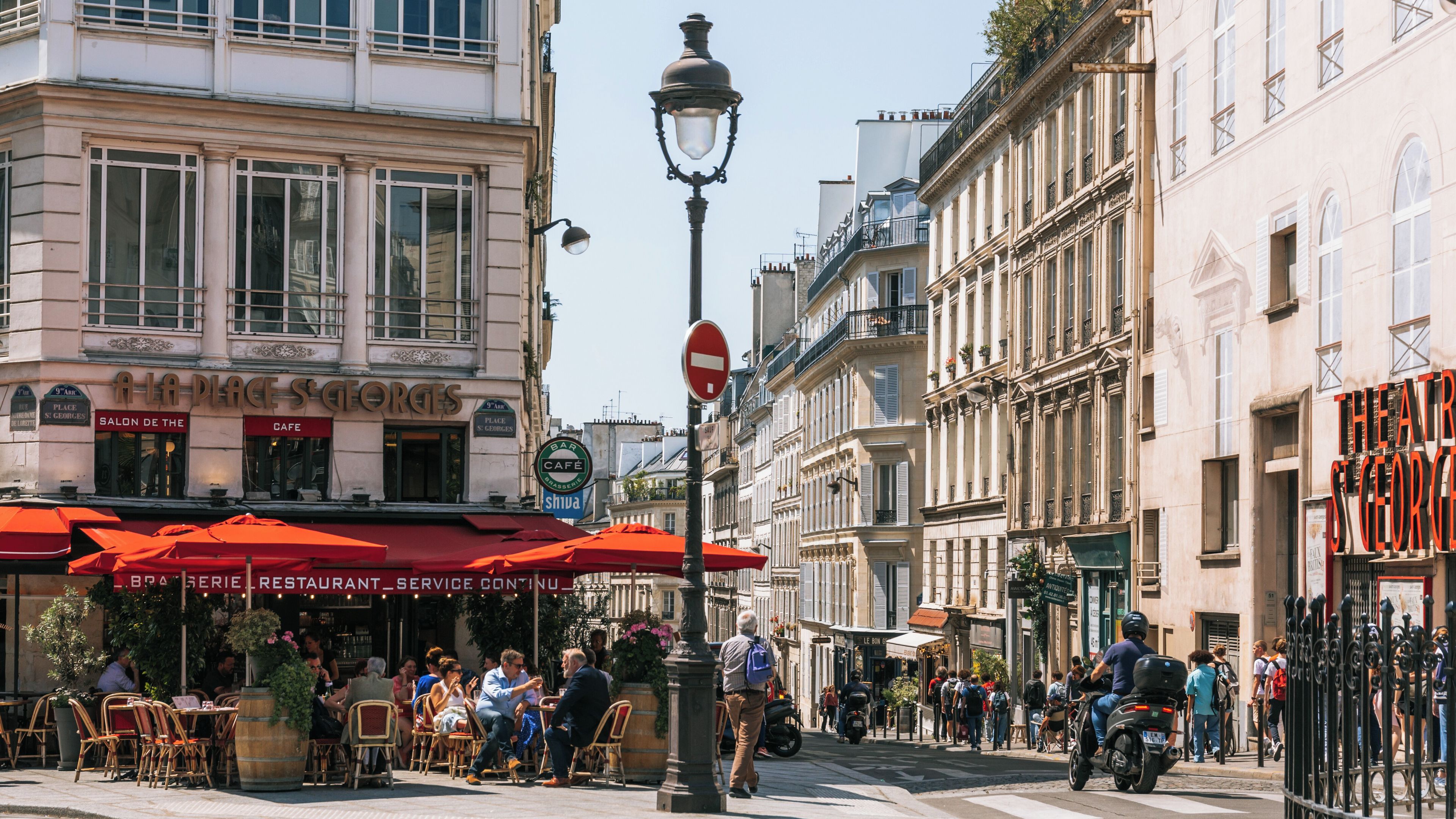 A bustling street scene with cafes, a no entry sign, and historic buildings.