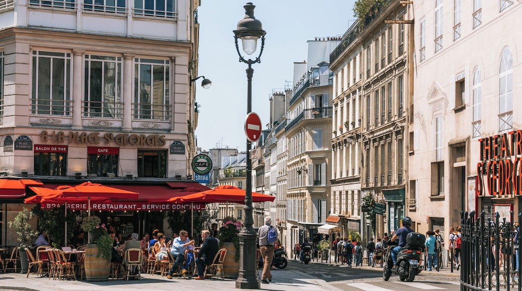 A bustling street scene with cafes, a no entry sign, and historic buildings.
