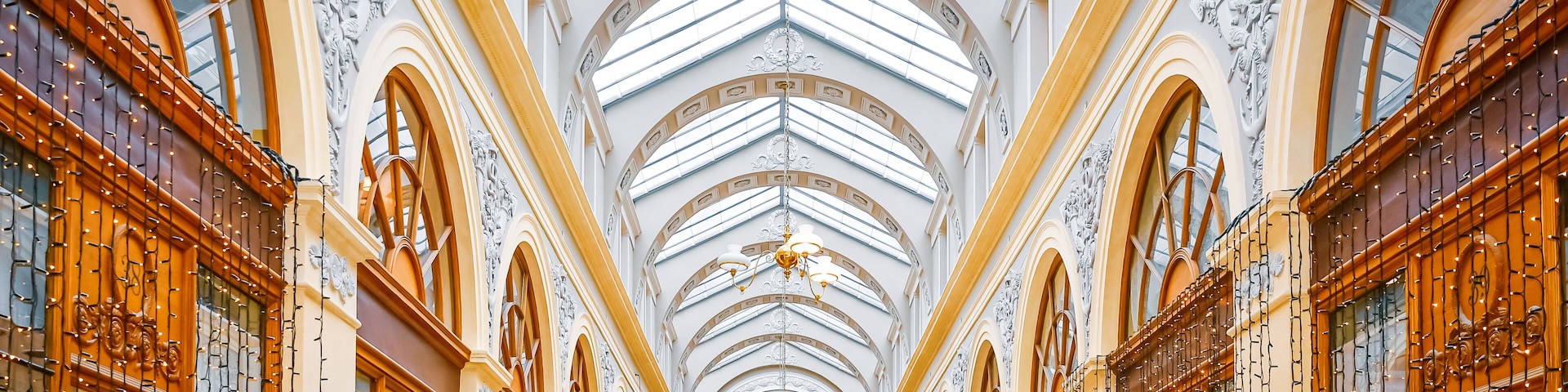 An ornate interior with a high arched ceiling, intricate wall carvings, and a central chandelier.