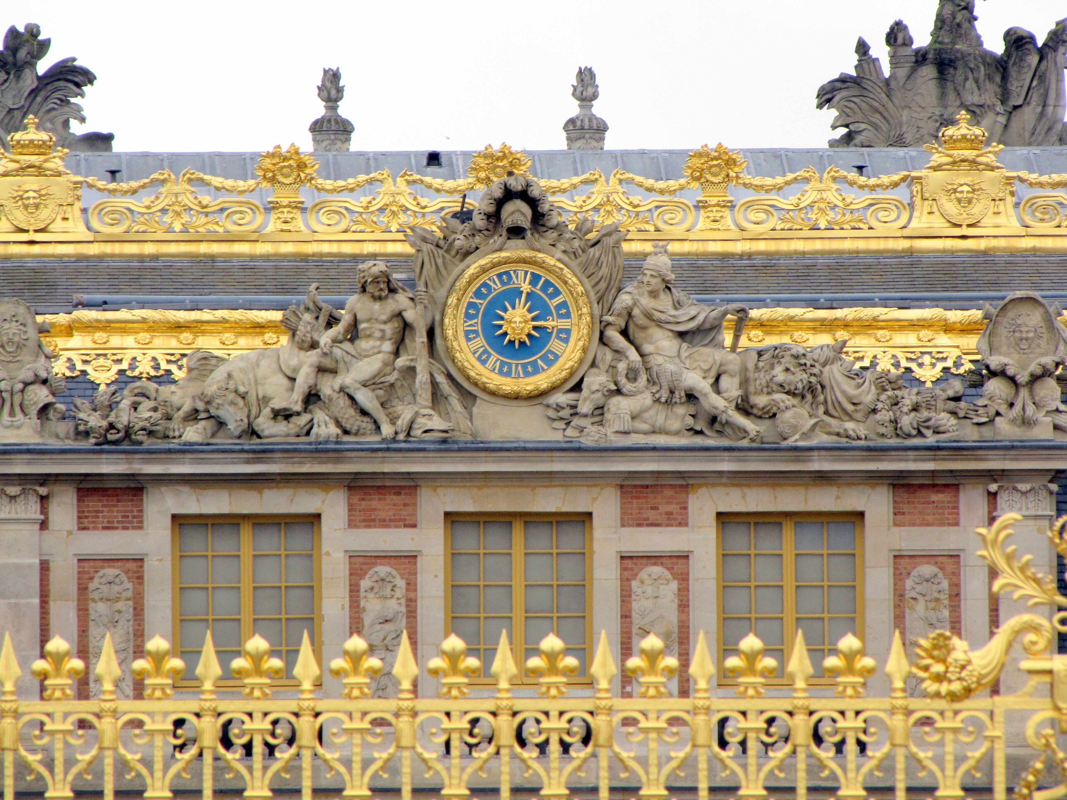 Un imposant bâtiment orné de décorations dorées, doté d’une grande horloge et de statues.