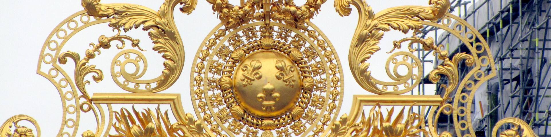 A golden ornate gate with a crown and floral designs.