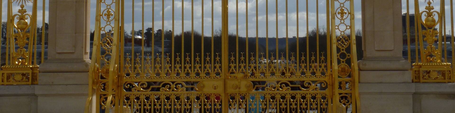 A golden ornate gate with intricate designs and a central emblem.