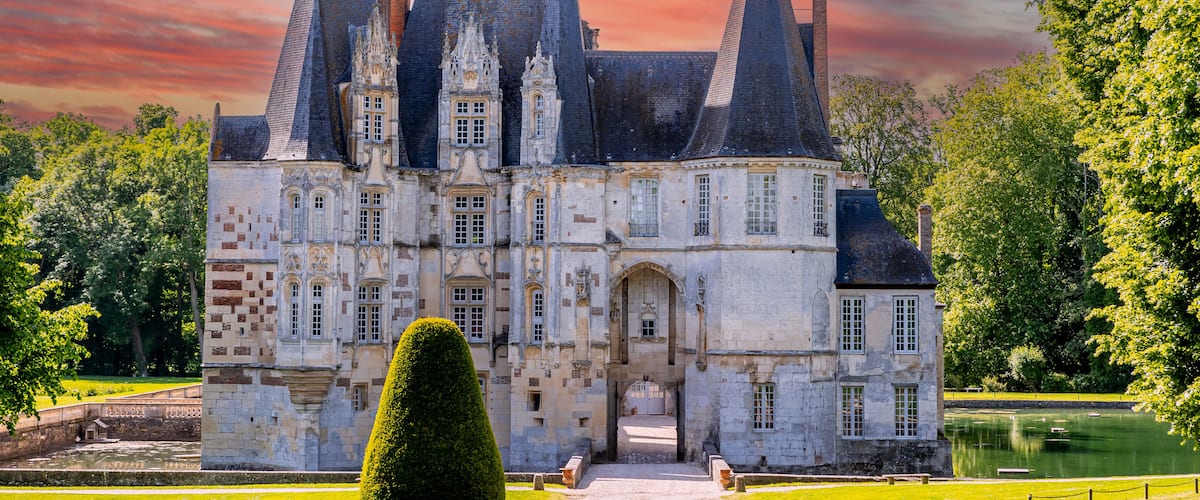 Un castillo histórico con múltiples torres y un jardín bien cuidado.