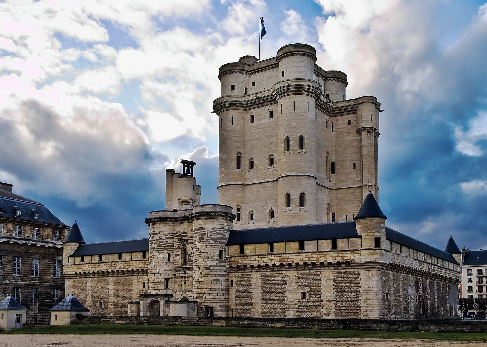 A large, historic stone castle with multiple towers and a flag on top.
