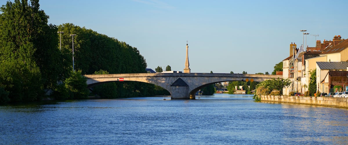 The historic stone Louis XV bridge and a war memorial obelisk across the Oise river in Compiègne, Picardy, France