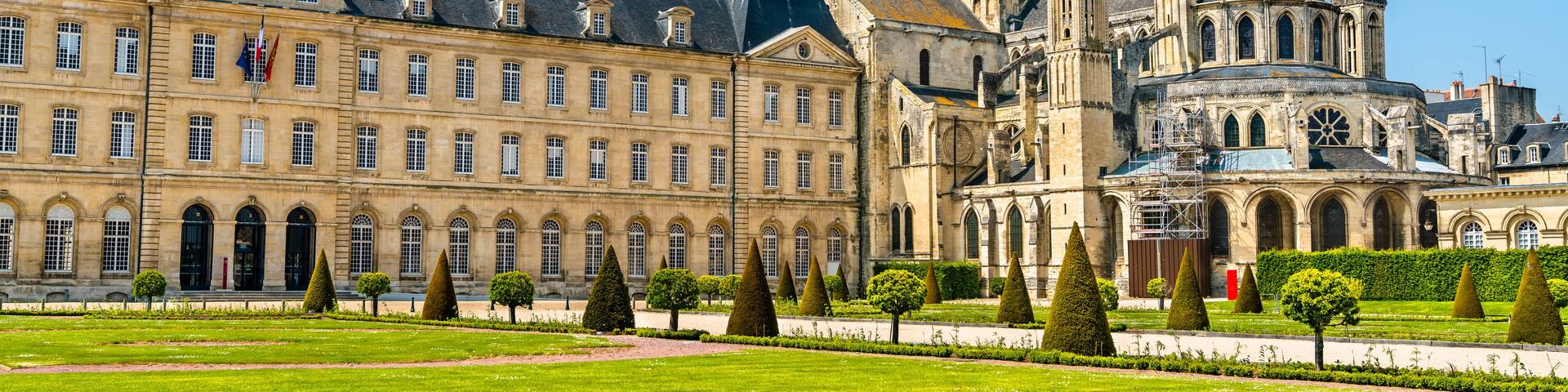 A historic building with multiple spires and a well-maintained garden.