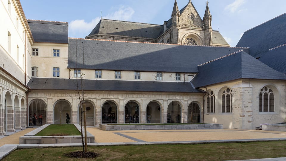 A historic building with a courtyard, arched walkways, and a prominent church tower.