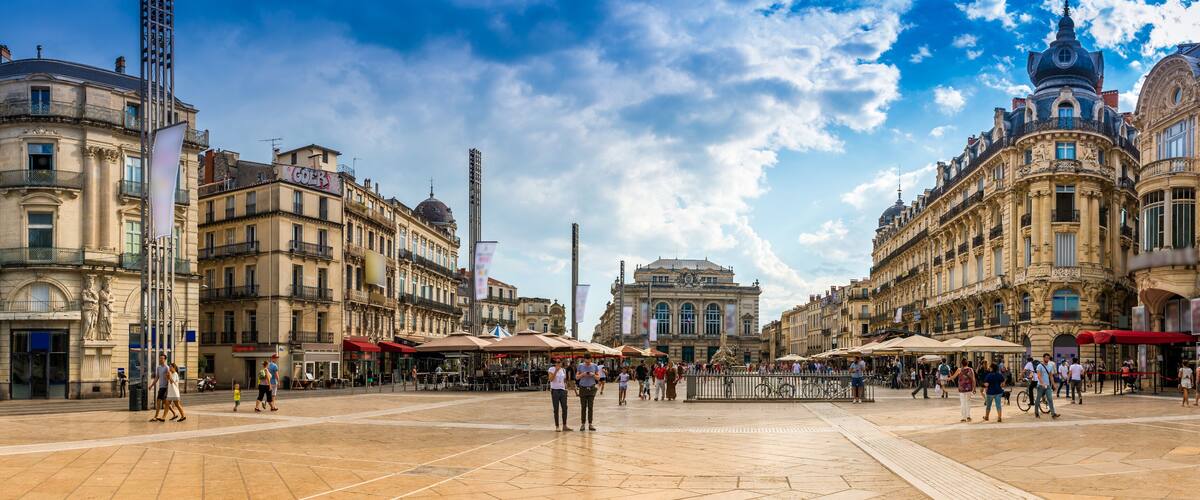 A historic square with ornate buildings, outdoor cafes, and a prominent statue.