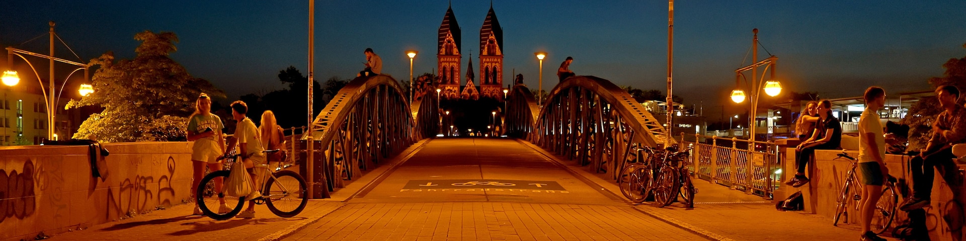Un puente de arquitectura gótica, un camino empedrado y farolas.