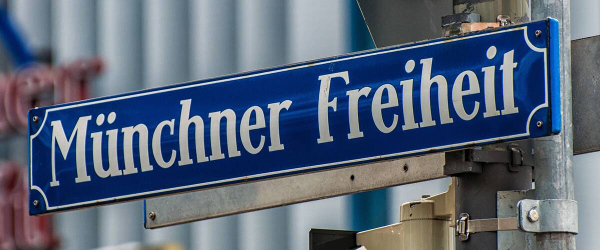 Ein Straßenschild mit der Aufschrift 'Münchner Freiheit', befestigt an einem Metallpfosten.