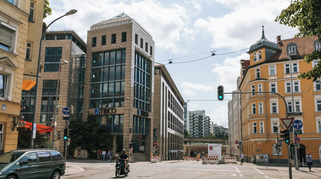 Cruzamento urbano com edifícios modernos, semáforo e uma motocicleta.