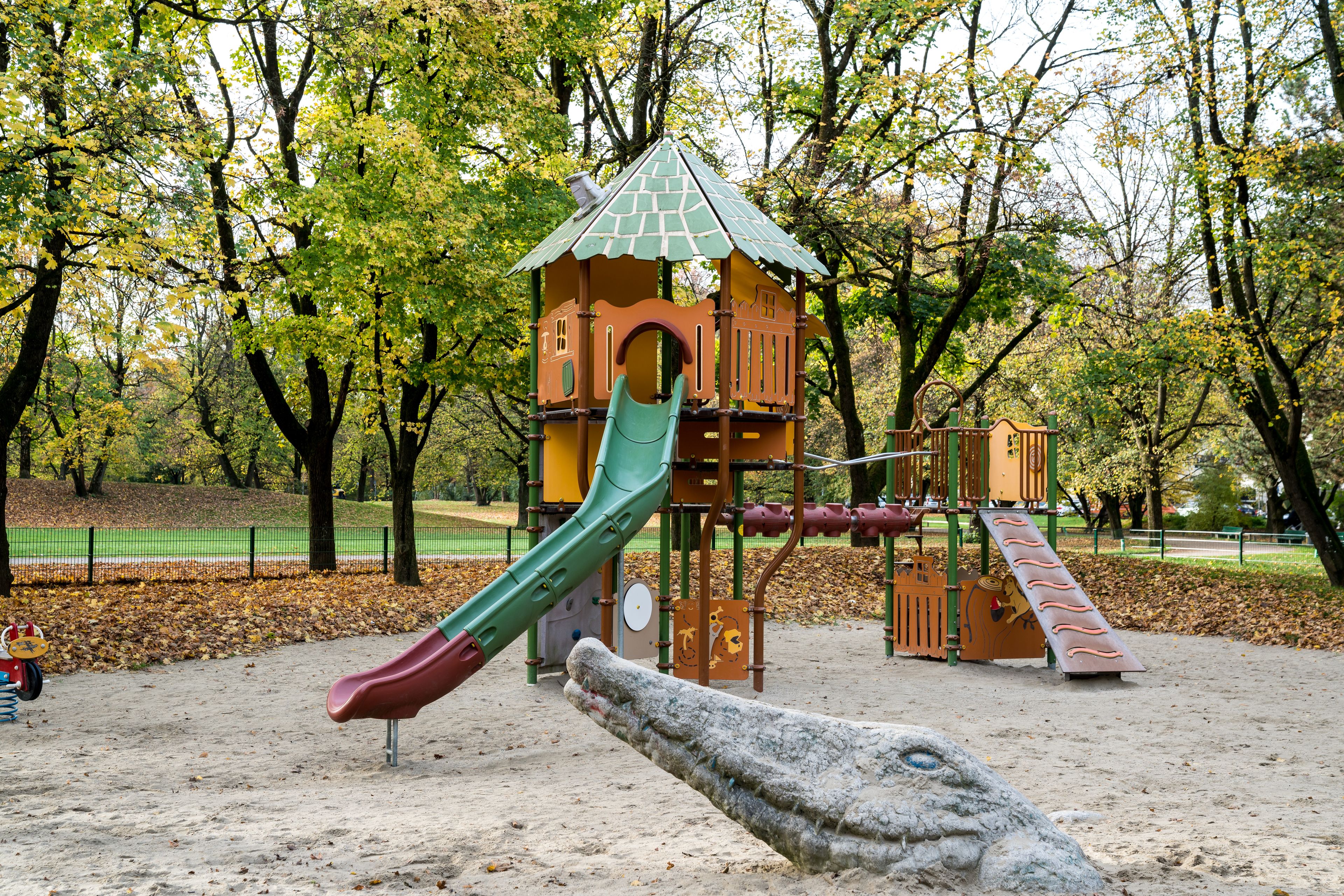 A playground with a slide, climbing structures, and a treehouse.